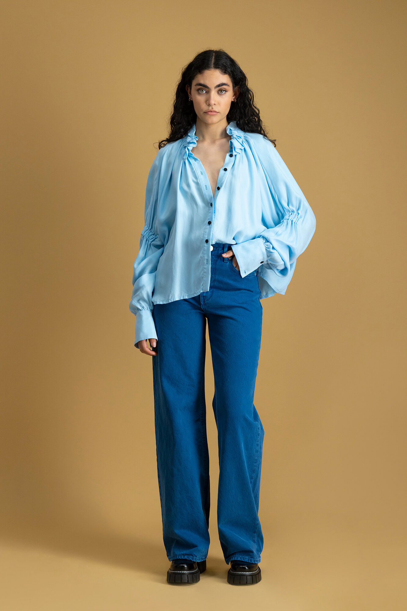 Model wearing blue outfit on brown background